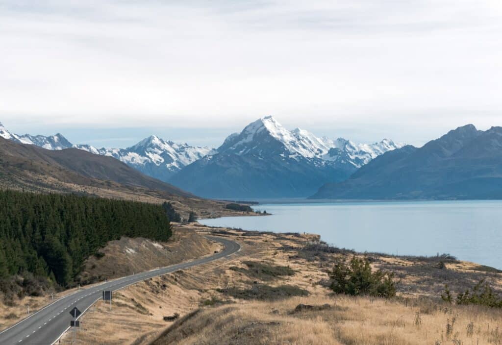 A road leading past a lake to the mountains of New Zealand