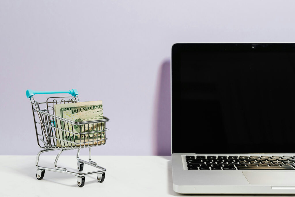 Shopping cart with a bunch of $20 bills next to a laptop